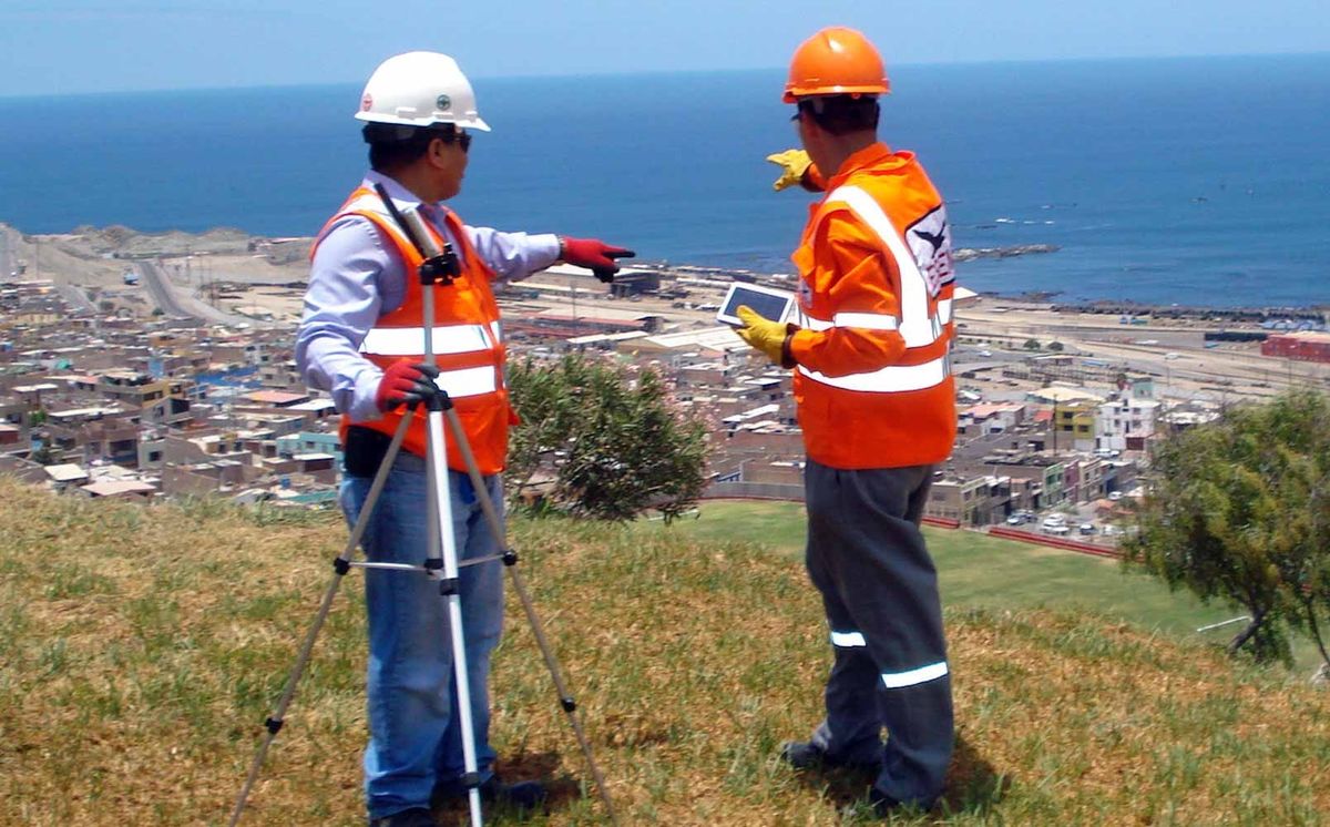Especialistas con chalecos reflectivos evaluando una zona costera con equipo topográfico